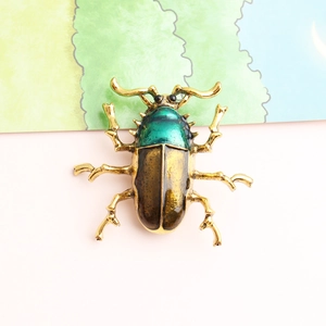 Macro shot of beetle brooch featuring green enamel wings and polished gold-plated legs