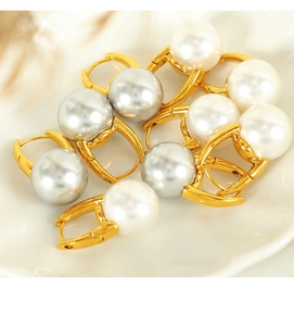 Macro detail of white and silver-grey pearl hoop earrings set on a white ceramic plate