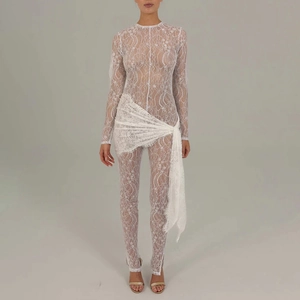 Detailed view of white sheer lace jumpsuit with long sleeves and matching lace wrap skirt