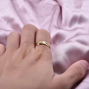 Minimalist gold irregular stainless steel ring shown on hand with pink silk background
