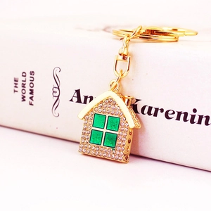 Golden rhinestone cartoon house keychain accessory with green windows on a book background