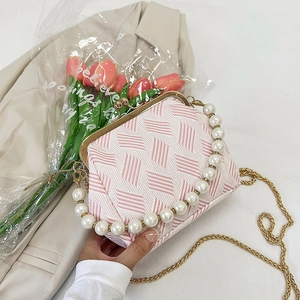 Detail of pink shell-shaped crossbody bag with pearl handle and golden chain strap