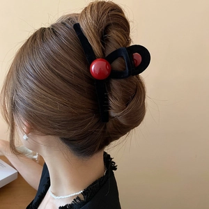 Detail showing a large red and black flocked hair claw clip worn on a bun hairstyle