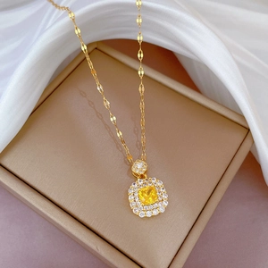 Vue macro d'un collier doré géométrique avec gemme jaune et pavé de diamants sur soie
