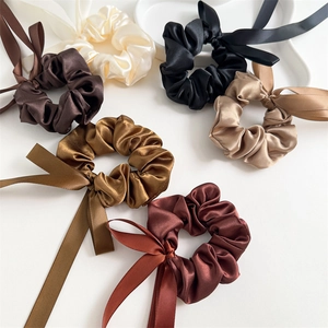 Detailed view of satin silk hair scrunchies with long ribbons in earthy neutral tones