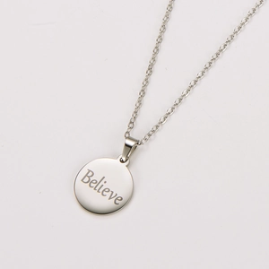 Detailed macro shot of silver round stainless steel pendant with Believe engraving