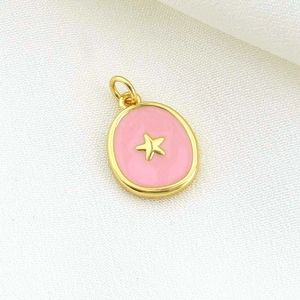 Detailed view of round gold star pendant with pink enamel inlay on textured fabric