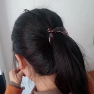 Close-up of a brown tortoiseshell banana hair clip securing a ponytail on a person