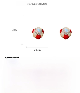 Macro detail of red and beige enamel flower earrings with pearl and rhinestone inlay