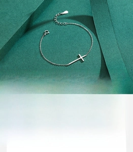 Macro detail of polished S925 sterling silver cross bracelet with fine chain links