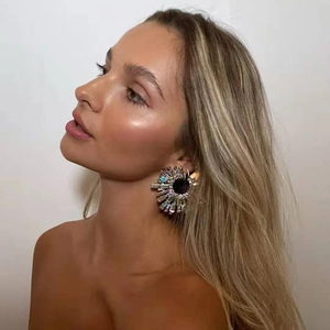 Close-up of a model wearing large radiant sunburst earrings with sparkling crystals