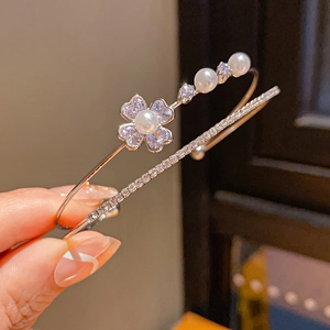 Detail of silver double-layer bracelet with pearl flower charm and pavé crystals