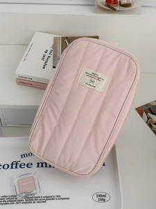 Dettaglio della trama trapuntata rosa e dell'etichetta tessuta beige sulla borsa portaoggetti