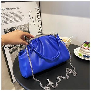 Détail du sac nuage plissé bleu royal avec fermoir métallique argenté dans un café chic
