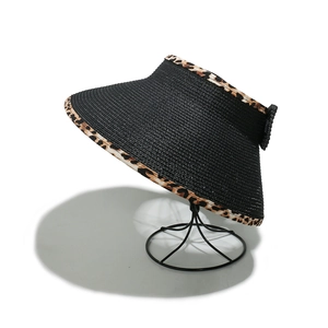 Macro detail of foldable straw sun hat with leopard print brim on a display stand
