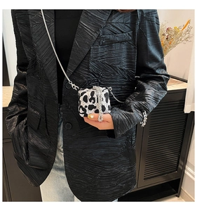 Mini leopard print crossbody bag with metal chain shown on model in black suit