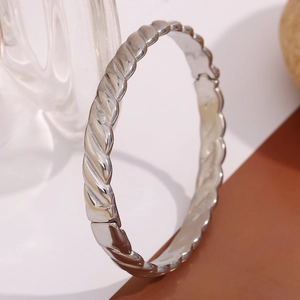 Détail d'un bracelet jonc argenté en acier inoxydable avec une texture torsadée unique