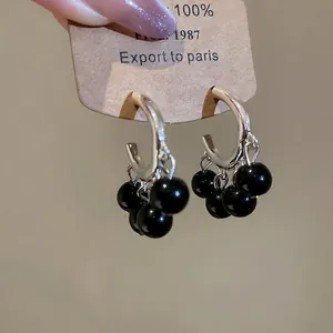 Retro silver circular earrings with hanging black polished beads on a display card