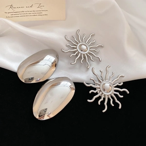 Detailed macro view of silver metallic sunburst and oval polished studs on silk