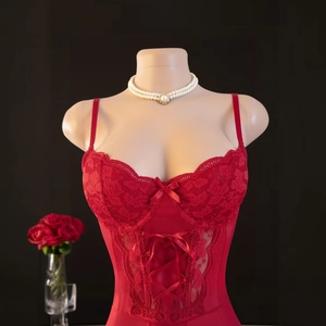 Détail d'un body en dentelle rouge avec nœuds décoratifs et fines bretelles sur mannequin