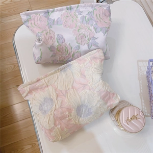 Detailed view of bubble jacquard fabric texture on pink and purple floral cosmetic bags