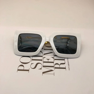 Flat lay of oversized white square sunglasses with dark grey lenses on typographic backdrop