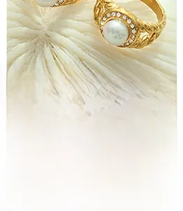 Detailed close-up of a golden pearl ring with sparkling rhinestones on coral texture