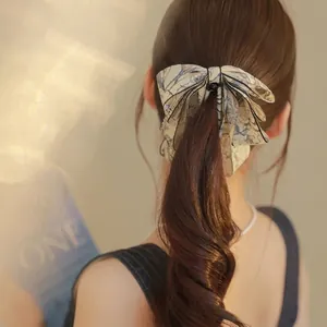 Elegant ink-wash floral bow hair clip worn by a model in a high ponytail