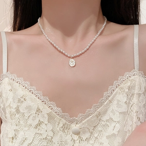 Detail of vintage tulip flower necklace with white oval pearl pendant on a gold chain