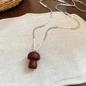 Dettaglio della collana con ciondolo a fungo in legno su lino con perline eleganti