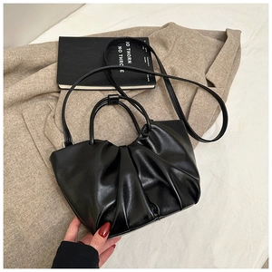 Detail of black pleated cloud bag texture with detachable shoulder strap and top handle