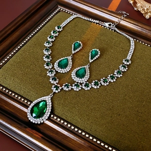 Dettaglio di set collana e orecchini a goccia smeraldo di lusso su velluto verde