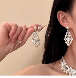 Detail shot of model wearing elegant floral pearl and diamond earrings with matching necklace