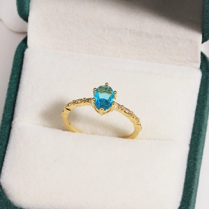 Detail of blue oval zircon ring with side diamonds in a green velvet jewelry box