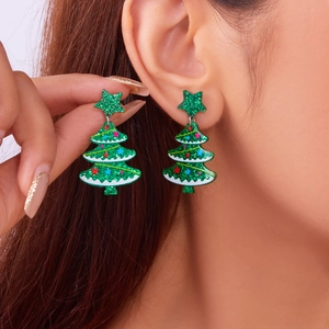 Detailed view of green glitter Christmas tree earrings worn on a model with sparkling star
