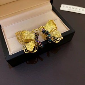 Exquisite golden butterfly stud earrings with iridescent beads on a jewelry gift box