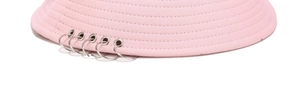 Détail d'un chapeau bob en coton rose avec cinq anneaux métalliques argentés sur le bord