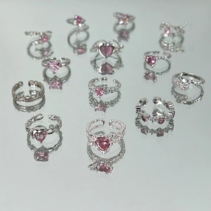 Silver rings set with pink heart zirconia and bow designs on reflective surface