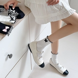 Detail of JK style Lolita socks with cute lace ruffles and black bowknots on white fabric