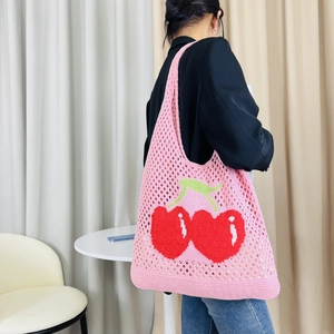 Close-up of pink knitted tote bag featuring a large cherry pattern and mesh texture