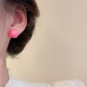Macro detail of glossy pink square stud earring with smooth ceramic texture on ear