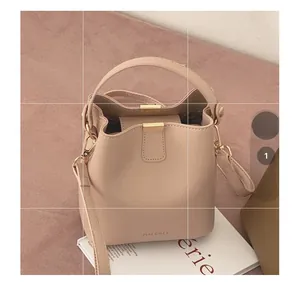 Detail of nude pink bucket bag with gold metal buckle and brand logo on fabric background