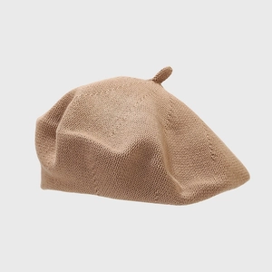 Detailed view of the brown knitted texture and top tip on this classic beret hat