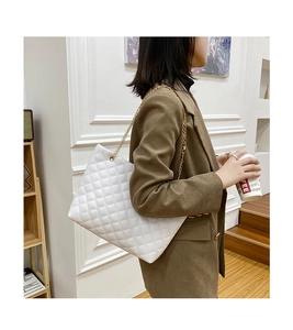 White quilted tote bag with golden chain strap shown in a side-view on model