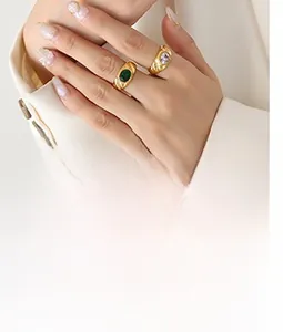 Detail of vintage gold C-shape rings with green and clear oval gems on a model's hand