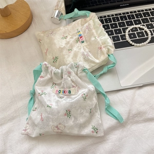 Detail of cartoon bear drawstring storage bag with soft floral print and mint green cords