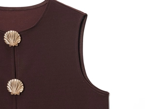 Close-up of shell-shaped golden metal button on dark brown vest top shoulder