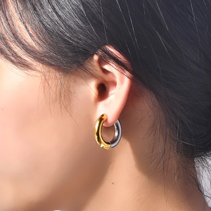 Minimalist two-tone gold and silver circular hoop earrings worn by a female model