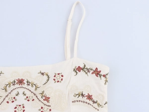 Detail of bohemian floral embroidery and adjustable strap on off-white linen dress