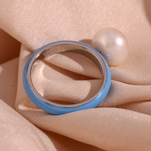 Close-up of a blue enamel ring with a large cream pearl on elegant satin fabric
